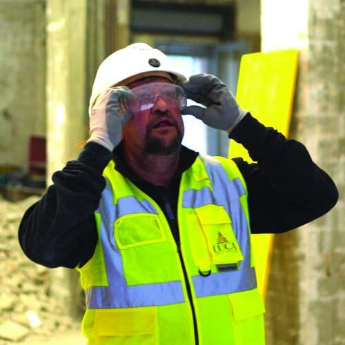 Tecnico in elmetto e gilet ad alta visibilità in cantiere