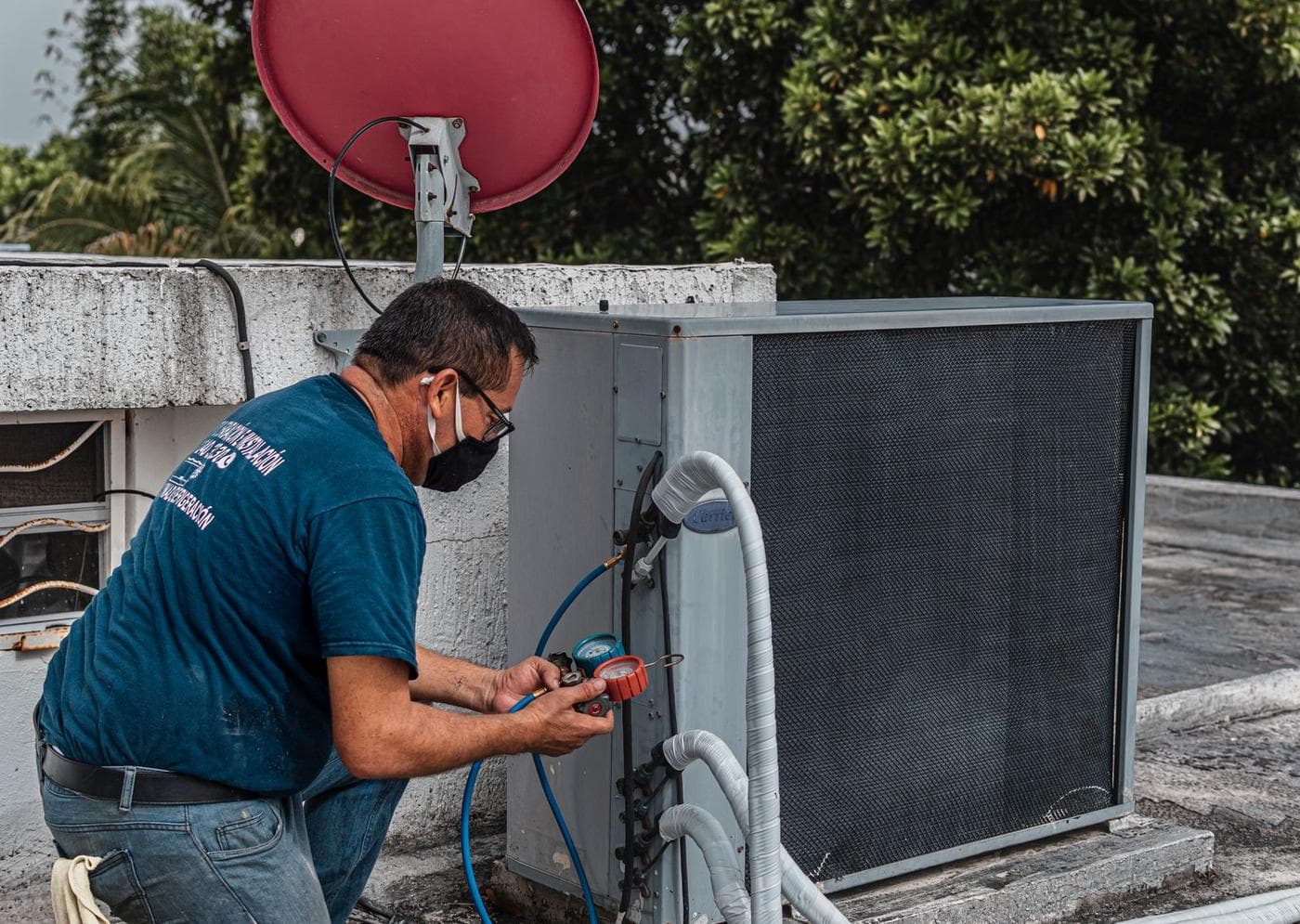 Tecnico con mascherina durante la manutenzione di un'unità esterna di climatizzazione
