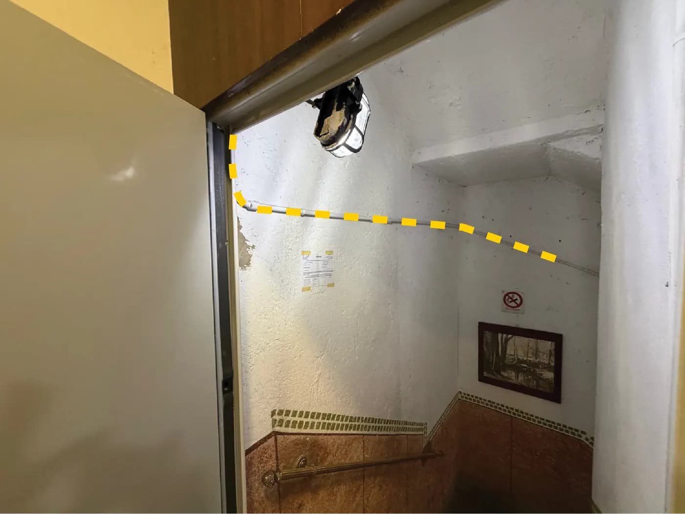 Apertura sul vano scale con una linea gialla tratteggiata che indica dove il cavo prosegue in un tubo protettivo in PVC